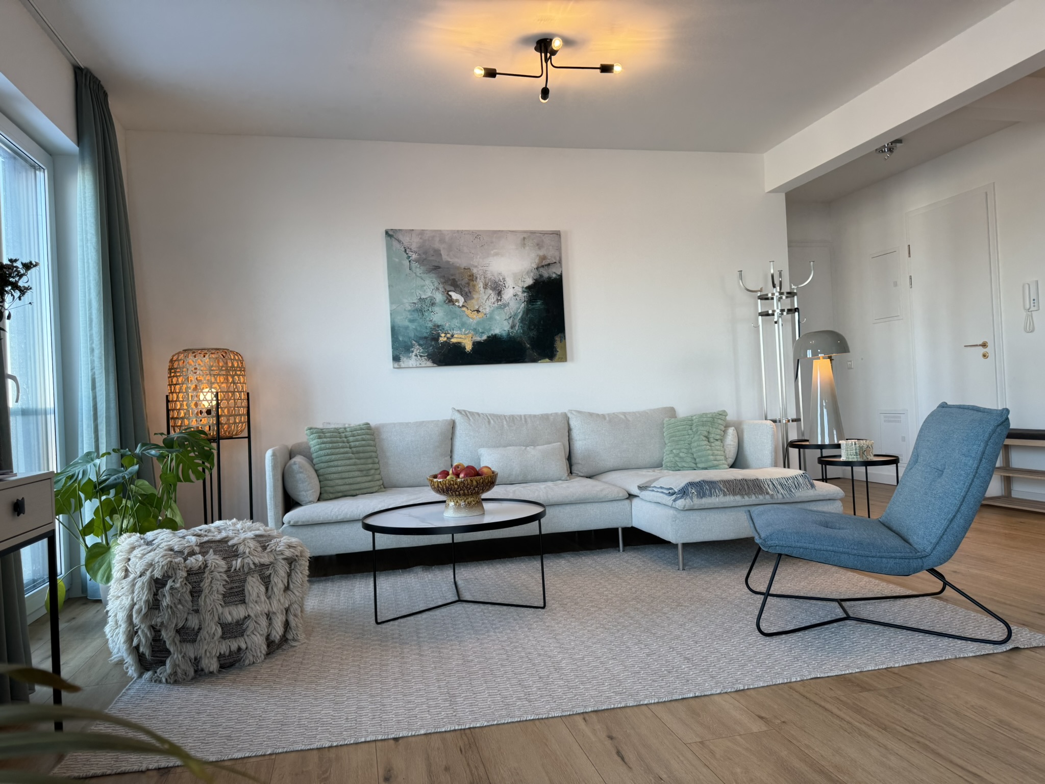 Helles Wohnzimmer der Ferienwohnung Möwe mit Sofa, Sesseln und Deko